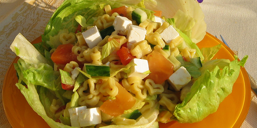 Salaatinlehtien päälle rakennettu fetajuusto-tomaatti-sydänpastasalaatti