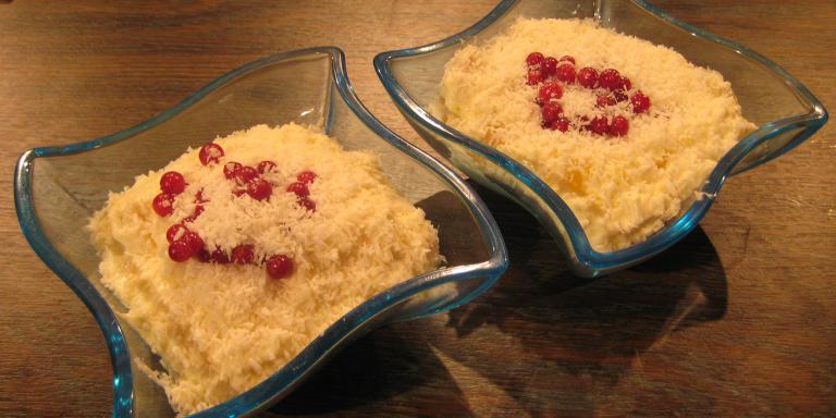 Kaksi annoskulhoa riisifrutista, pinnalla kookoshiutaleita ja punaisia marjoja