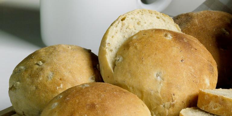 Kaksi sämpylää ja yksi halkaistu sämpylä pöydällä