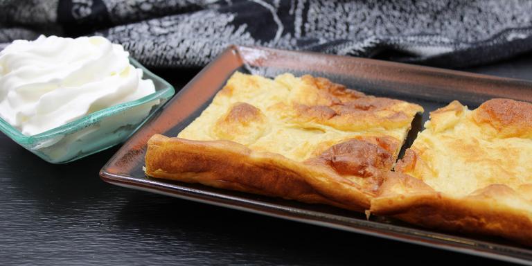 Kaksi pannukakkupalaa lautasella, vieressä kermavaahtoa kipossa