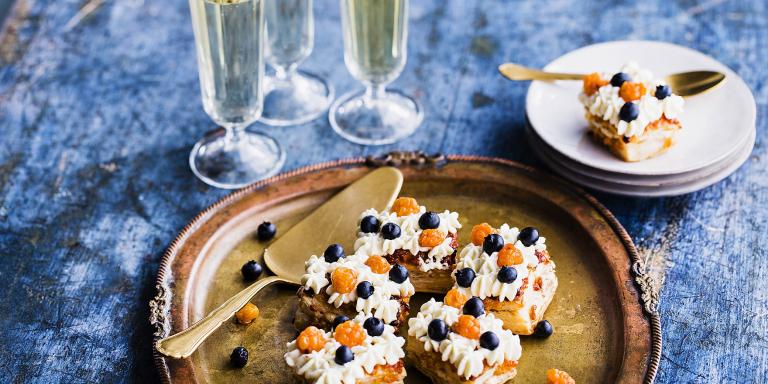 Mustikka-lakka koristellut leivokset tarjottimella sekä annos, 3 kuohuviinilasia