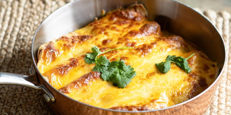 Pannulla juustokuorrutettuja, täytettyjä tortillaletturullia, pinnalla korianteria.