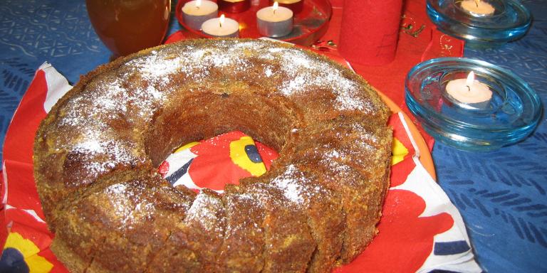 Rengasmuotissa paistettu kahvikakku, joka on viipaloitu ja pintaan on ripoteltu tomusokeria. Jouluinen pöytä koristeltu tuikkukynttilöin.