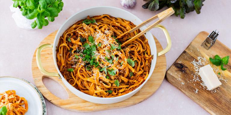 Padallinen tagliatelle al Ragúa pöydällä parmesaanin ja basilikaruukun kera
