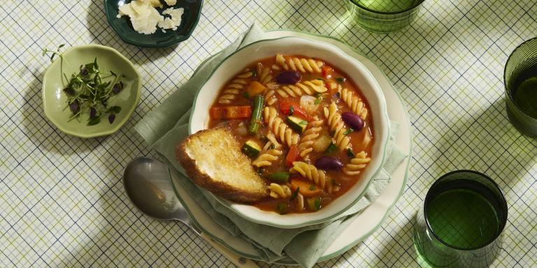 Kulhollinen kasvisminestronekeittoa katettuna pöytään