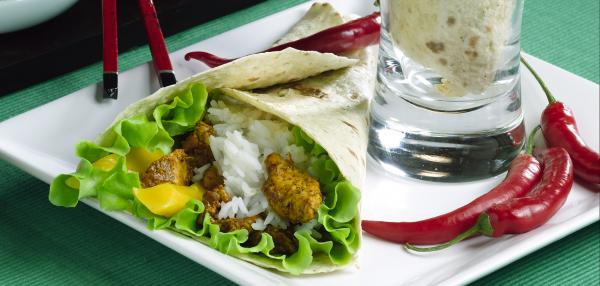 Lautasella kääritty liha-riisitäytteinen tortilla ja chilipaprikoita.