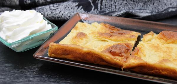 Kaksi pannukakkupalaa lautasella, vieressä kermavaahtoa kipossa