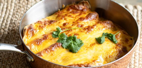 Pannulla juustokuorrutettuja, täytettyjä tortillaletturullia, pinnalla korianteria.