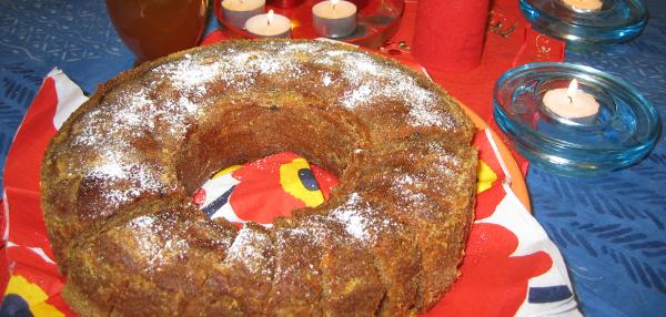 Rengasmuotissa paistettu kahvikakku, joka on viipaloitu ja pintaan on ripoteltu tomusokeria. Jouluinen pöytä koristeltu tuikkukynttilöin.