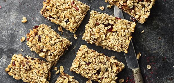 Pöydällä paloiksi leikattuja hedelmä-marjamyslipatukoita ja veitsi.