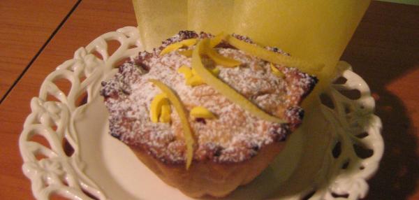 Sitruunankuorisuikaleilla ja tomusokerilla koristeltu murotaikinaleivos. Leivos on paistettu leivosmuotissa ja siinä on taikinakansi.