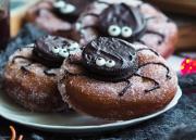 Halloween-donitsit, joissa donitsin päälle on keksistä koristeltu hämähäkki.