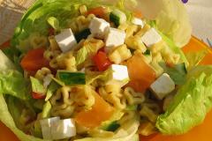 Salaatinlehtien päälle rakennettu fetajuusto-tomaatti-sydänpastasalaatti