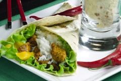 Lautasella kääritty liha-riisitäytteinen tortilla ja chilipaprikoita.