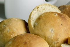 Kaksi sämpylää ja yksi halkaistu sämpylä pöydällä