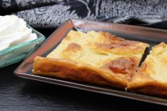 Kaksi pannukakkupalaa lautasella, vieressä kermavaahtoa kipossa