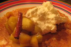 Lautasella pitsireunainen lettu, omenakuutiohilloketta, kanelitanko ja kermavaahtoa