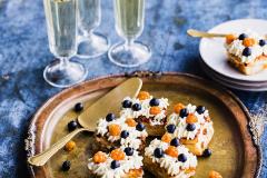 Mustikka-lakka koristellut leivokset tarjottimella sekä annos, 3 kuohuviinilasia