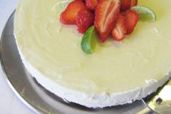 Pyöreä muropohjainen juustokakku, vaalea tuorejuustotäyte ja päällä kuohuviinistä tehty kiillepinta. Koristeltu mansikoilla.