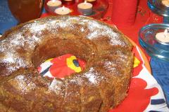 Rengasmuotissa paistettu kahvikakku, joka on viipaloitu ja pintaan on ripoteltu tomusokeria. Jouluinen pöytä koristeltu tuikkukynttilöin.