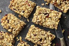 Pöydällä paloiksi leikattuja hedelmä-marjamyslipatukoita ja veitsi.