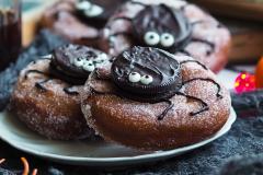 Halloween-donitsit, joissa donitsin päälle on keksistä koristeltu hämähäkki.