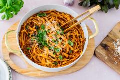 Padallinen tagliatelle al Ragúa pöydällä parmesaanin ja basilikaruukun kera